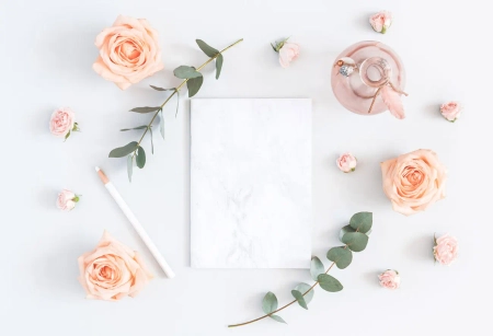 Helle Karte mit Rosen, Eukalyptus und Stift auf weißem Hintergrund