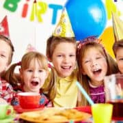 Fünf Kinder mit Partyhüten feiern einen Geburtstag