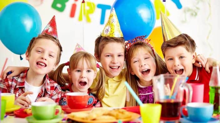 Fünf Kinder mit Partyhüten feiern einen Geburtstag