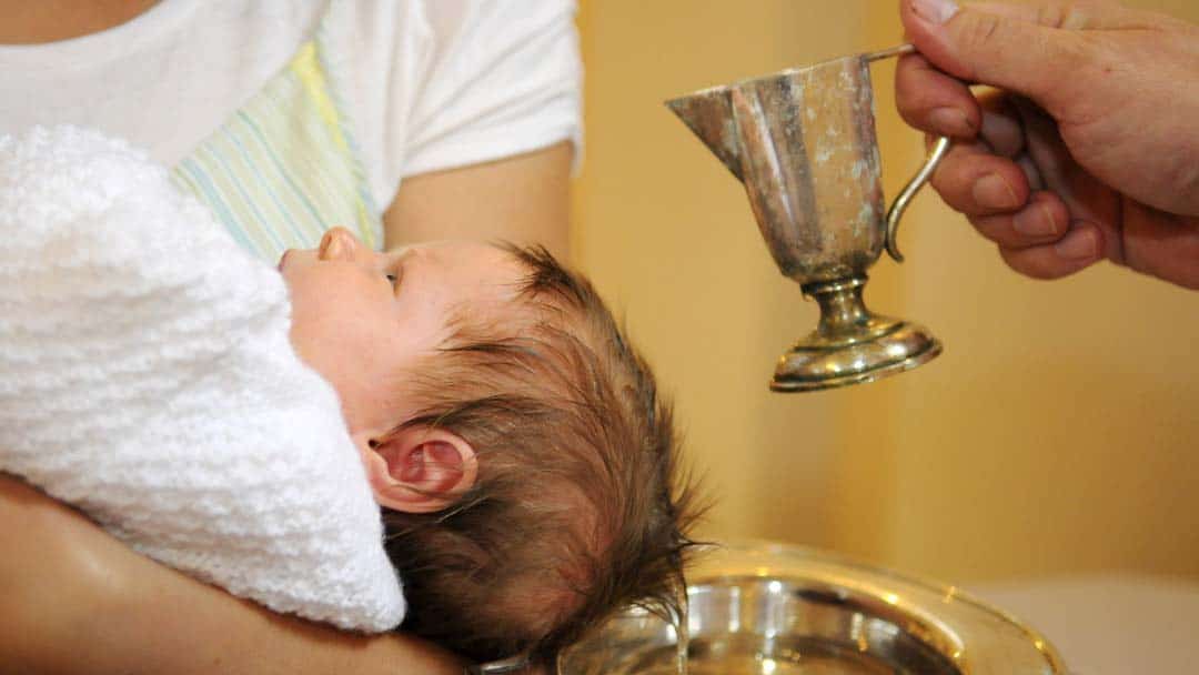 Baby über Taufbecken mit Taufkelch